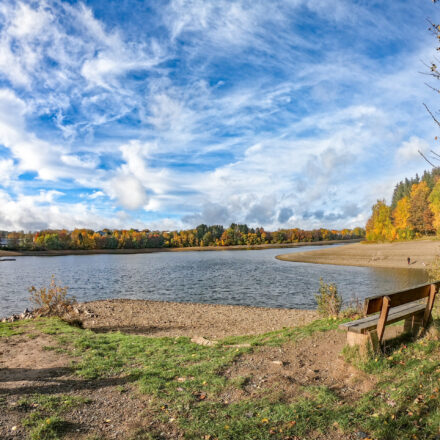 See mit niedrigem Wasserstand und 2 Bänken und Blick auf den Bootshaus von Worriken