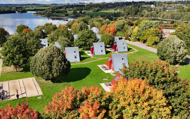 Ferienwohnungen vom Sport- und Ferienpark Worriken im Herbst. Auf dem Hintergrund ist den Staumauer vom Bütgenbacher See zu sehen.