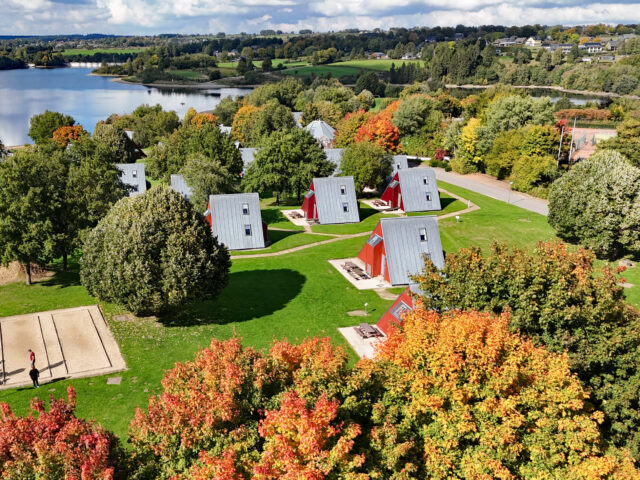 Ferienwohnungen vom Sport- und Ferienpark Worriken im Herbst. Auf dem Hintergrund ist den Staumauer vom Bütgenbacher See zu sehen.