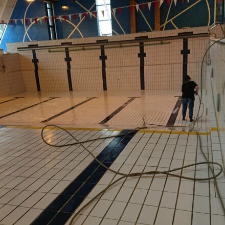 Woman cleaning an empty swimming pool