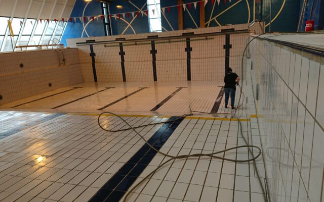 Une femme qui nettoie dans une piscine vide