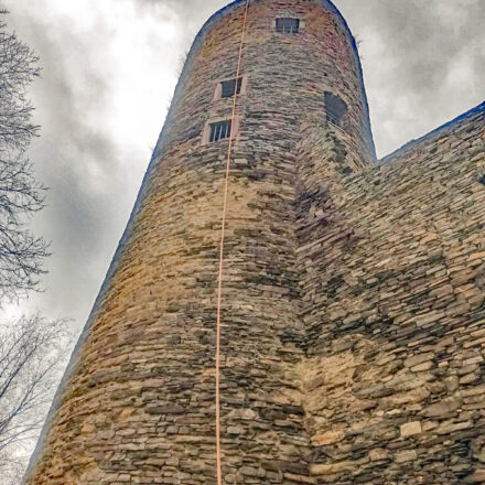 Foto aus der Froschperspektive, das die Höhe des Turms betont. Von der Spitze des Turms baumelt ein Kletterseil herab, das andeutet, dass sich hier jemand abseilen wird.