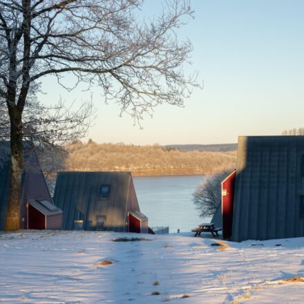 Ferienhaus Worriken im Winter. Im Hintergrund sieht man einen See und einen Discgolfkorb