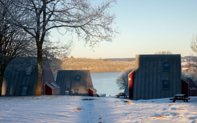 Ferienhaus Worriken im Winter. Im Hintergrund sieht man einen See und einen Discgolfkorb