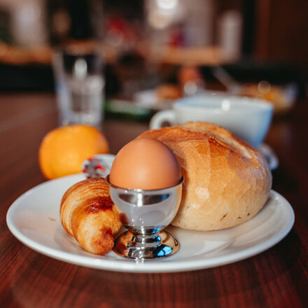 Teller mit einem Ei, Croissant und ein weisses Brötchen