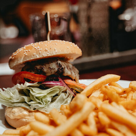 Hamburger mit Fritten auf einem Teller. Auf dem Hintergrund sieht es aus wie ein Restaurant