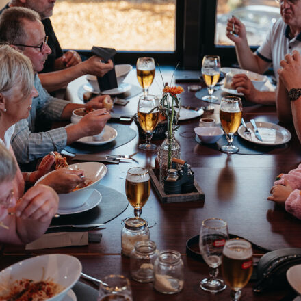 Verschiedene Menschen sitzen und essen an einem Restauranttisch