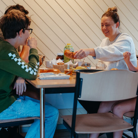 Family around a table with cereals and fresh bread on it.